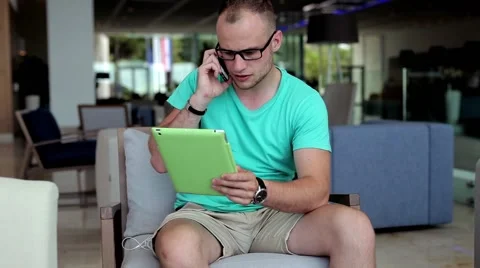 Young man with tablet pc and smartphone in hotel lobby. Stock Footage 55281489