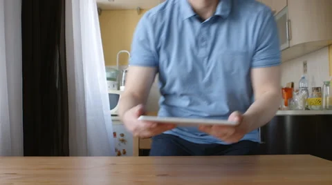 A young man with a tablet PC goes to the table and sits Видео 66466119