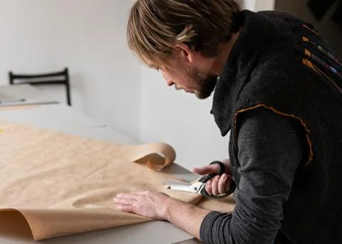 Young man tailor with scissors making clothing pattern Stock Photos