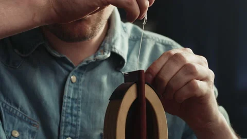 Young man tailor sewing two pieces of leather on stand close-up, using Stock Footage 157237038