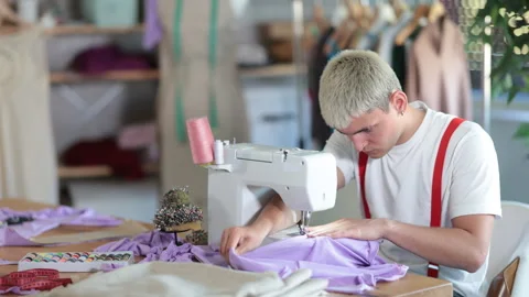 Young man tailor sews clothes on a sewing machine in the workshop. Fashion Stock Footage 326315171