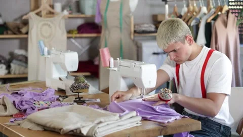 Young man tailor sews clothes on a sewing machine in the workshop. Fashion Stock Footage 331307249