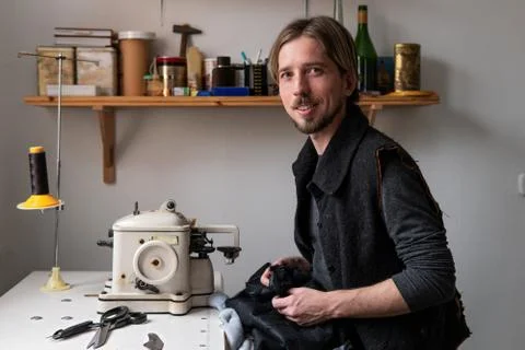 Young man tailor smiling at workplace in sewing workshop Stock Photos