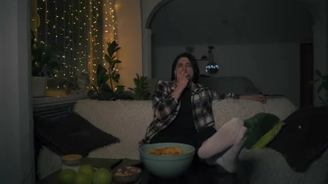 A young man takes an apple from the table and starts eating it, watching a movie 库存影片 170423121