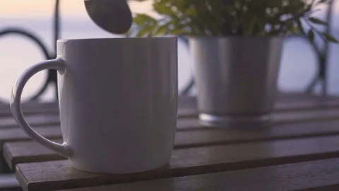 Young man takes cup of coffee near sea at sunny morning Stock Footage 85209316