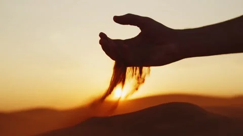 Young man takes a handful of sand from the desert and pours it Stock Footage 305723040