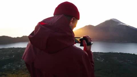 A young man takes on an hendy camera a mountain landscape. A man in a red hat Stock Footage 130755246