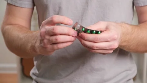 A young man takes out a tablet, pill from a blister pack. The concept of health Stock Footage 236921289