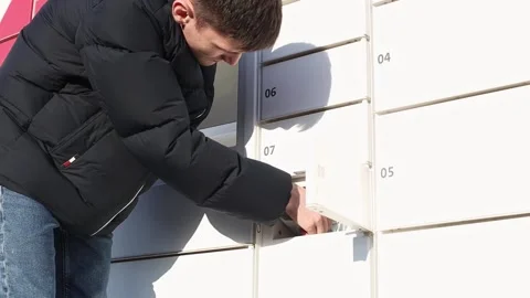 The young man takes the parcel from the box. Video stock 237254688