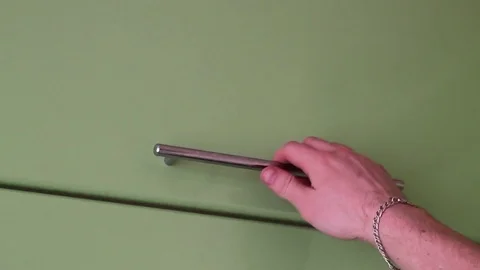 The young man takes puts a plate in the utensil drawer 動画素材 73348243