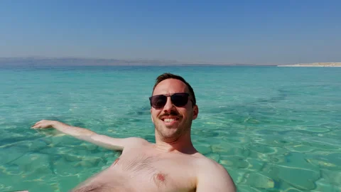 Young Man Takes Selfie while on Holiday Floating in the Dead Sea. Israel, Stock Footage 254763078