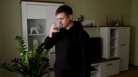 The young man takes two pills and washes them down with water. Stock Footage 231814351