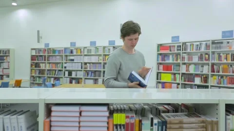Young Man Taking Book from Bookshelf in Library Stock Footage 63045137
