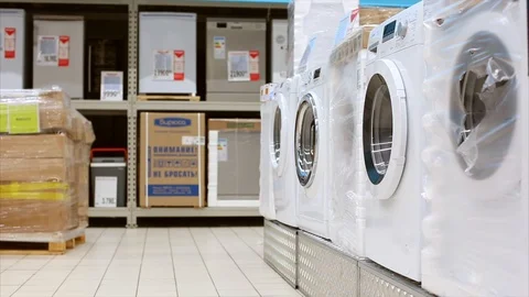 Young man taking clothes out of washing machine in big store. Comic video Stock Footage 107342298