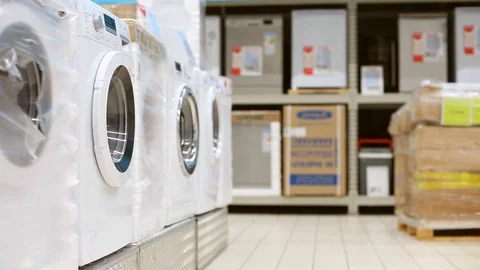 Young man taking clothes out of washing machine in big store. Comic video Stock Footage 107342370