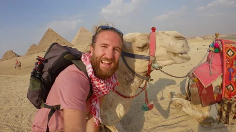 Young man taking cool selfies with a camel at the Great Pyramids of Giza Stock Footage 164810625