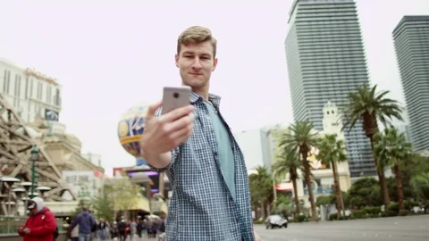 Young man is taking a few selfies while standing on a street of Las Vegas Stock Footage 76165863