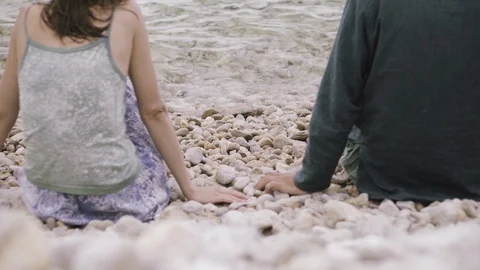 Young man taking hand of a young woman while sitting on the beach Stock Footage 127696559