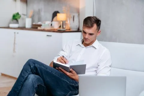 Young man taking notes sitting on the couch . Stock Photos