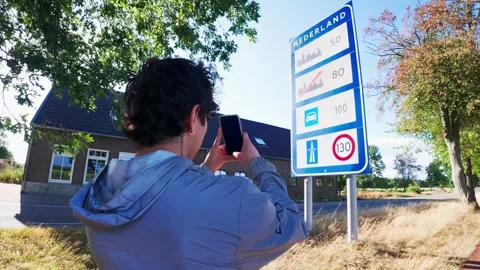 Young Man Taking a picture of Netherlands Border Speed Limit Sign on Smartphone. Stock Footage 345377582