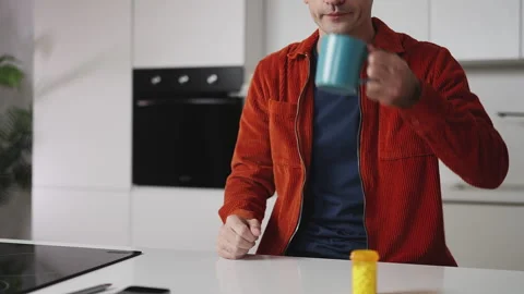 Young man taking a pill with water at home, health supplement concept Stock Footage 337907792