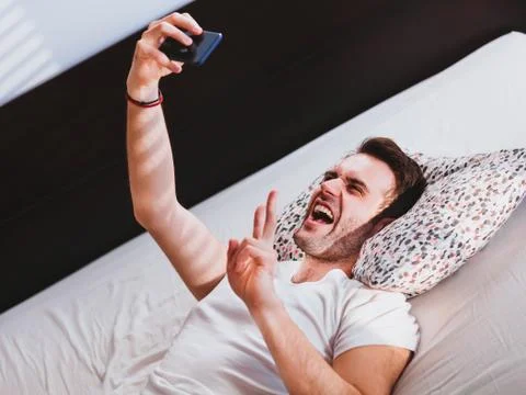 Young man taking a selfie in the bed Stock Photos