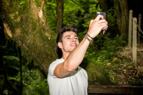 Young Man Taking Selfie with Cell Phone in Forest Stock Photos