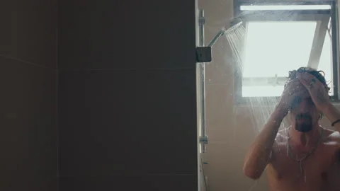 Young man taking a shower, day light Stock Footage 235659037