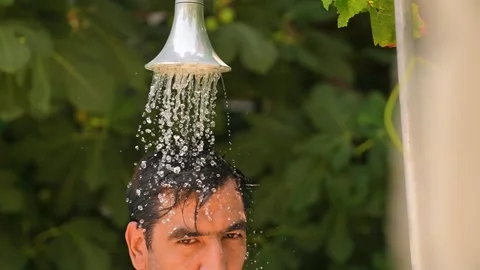 Young man taking shower in hot summer weather Video stock 280491739