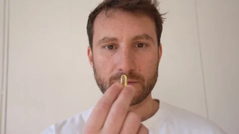 Young man taking a vitamin supplement pill Vidéo 328227898