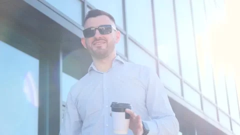 A young man talking to the camera while holding a smartphone and coffee in his Stock Footage 252895511
