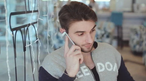 Young man talking on cell phone in cafe Stock Footage 63067958