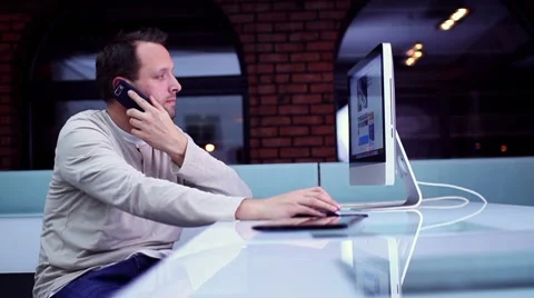 Young man talking on cellphone in front of computer HD Stock-Footage 10743020
