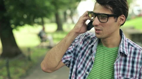 Young man talking on cellphone in the park, steadicam shot HD Stock-Footage 11823947