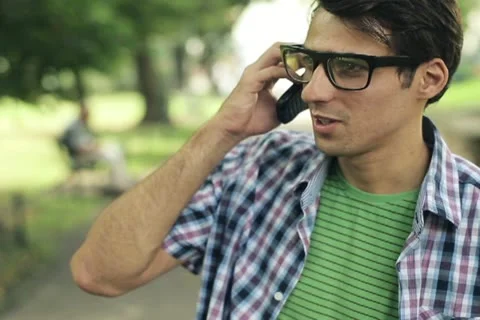 Young man talking on cellphone in the park, steadicam shot NTSC Stock Footage 11823969