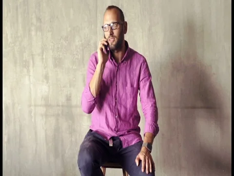 Young man talking on cellphone sitting in the studio Stock Footage 77066326