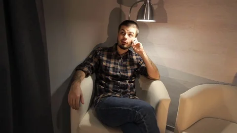 Young man talking on cellphone while sitting on couch at home Stock Footage 70758546