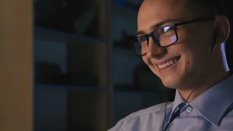 A young man talking on facetime, video chat, dark background, close-up Stock Footage 98301482