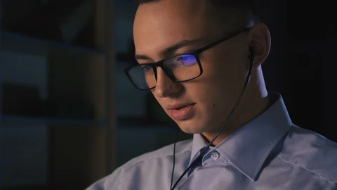 A young man talking on facetime, video chat, dark background, close-up Stock Footage 98301911