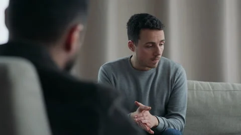 Young man talking to his therapist at therapy session Stock Footage