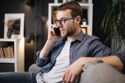 Young man talking on mobile on couch Stock-Fotos