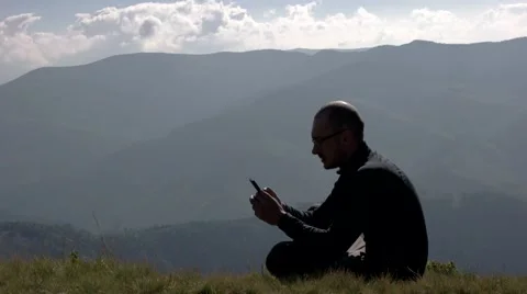 Young Man is Talking on a Mobile Phone on a Mountain Landscape Background Stock Footage 65420306