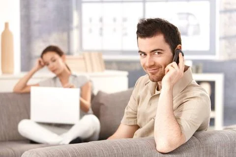 Young man talking on mobile smiling Young man sitting on sofa at home, tal... Stock Photos