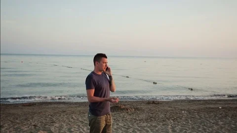 Young man talking on the phone on the beach Stock Footage 77055437