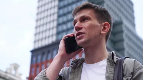 A young man talking on the phone. Close-up. A busy city street Stock Footage 246088952