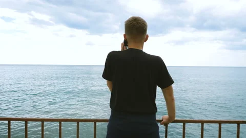Young man talking on the phone looking at the sea. Stock-Footage 97384492