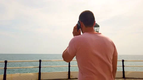 Young Man Talking On The Phone Looking At The Sea. Stock Footage 203189878
