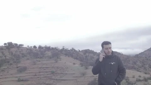 Young Man Talking on Phone on Misty Mountain Hilltop, Tiznit, Morocco Stock-Footage 332770076