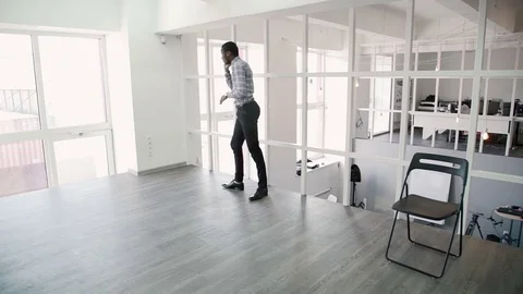 Young man is talking on phone, walking around modern office. Stock Footage 82172135