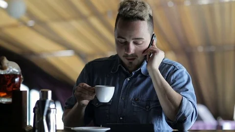 A young man talking on the phone while sitting at the bar Stock Footage